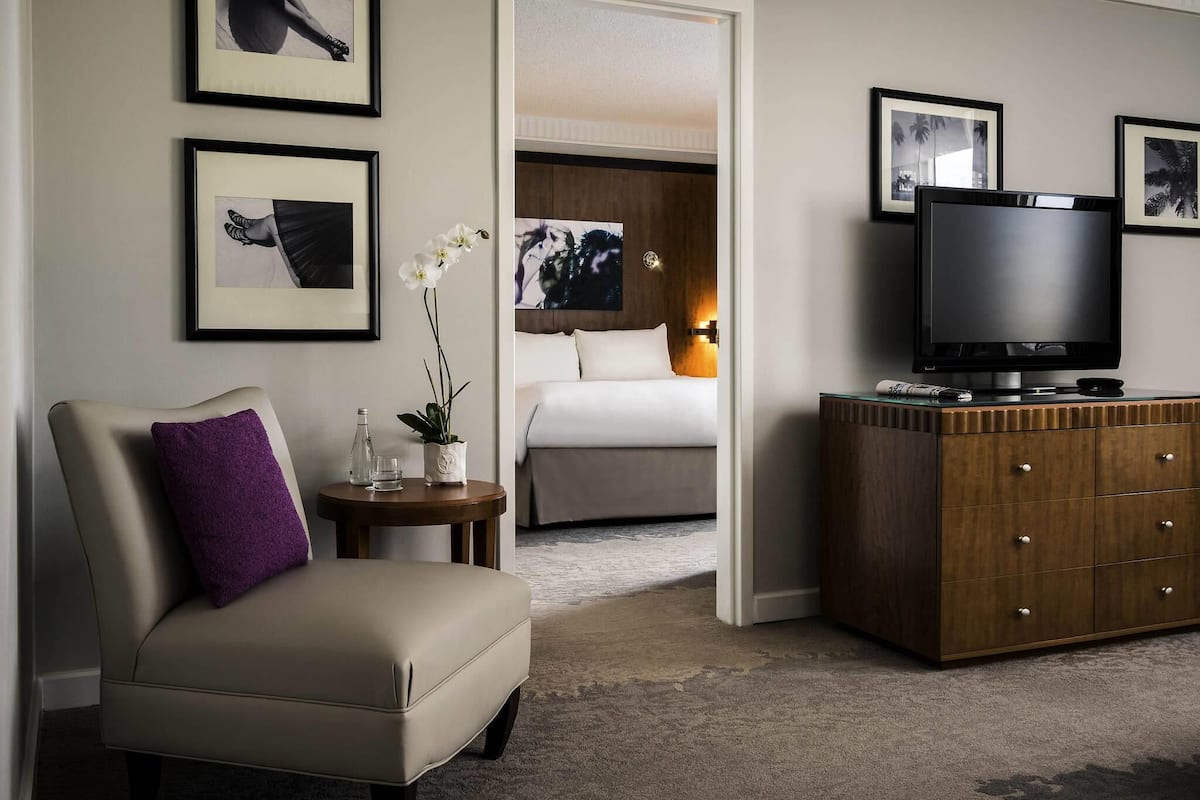 Hotellihuone, jossa on sänky, televisio, lipasto ja seinillä tauluja.