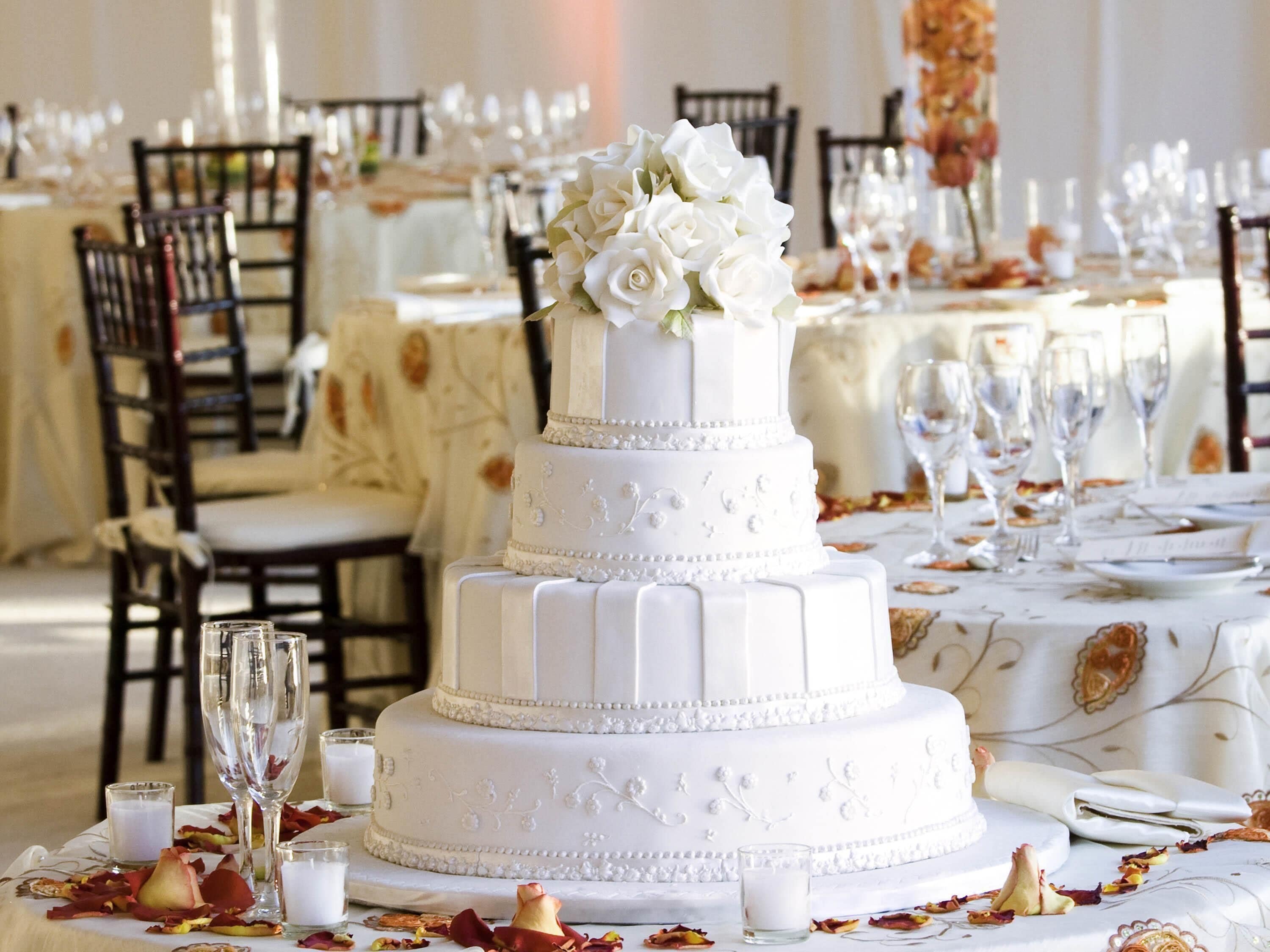 A multi-tiered white cake with floral decorations on a table set for a formal event.
