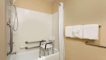 A bathroom with a bathtub, grab bars, a showerhead, a white towel rack, and a white shower curtain.