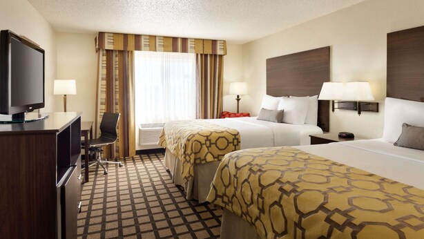 A hotel room with two beds, a desk with a television, and a chair. - Baymont by Wyndham Salina (Salina)