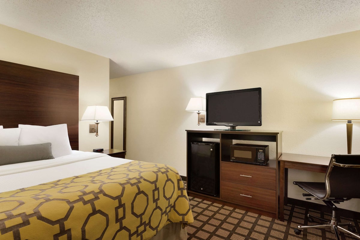 A hotel room with a bed, a desk with a computer, a TV, and a microwave.