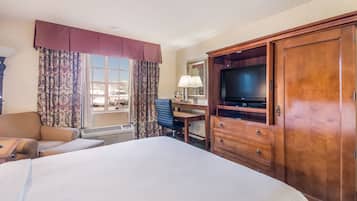 A hotel room with a large bed, a desk, a television, and a wardrobe.