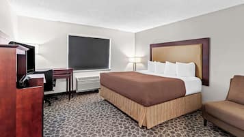 Ein Hotelzimmer mit Bett, Schreibtisch, Stuhl, Lampe und einem großen Fenster.