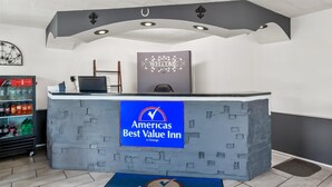 Uma mesa de recepção com uma placa de 'Welcome' e o logotipo de 'Best Value Inn'.