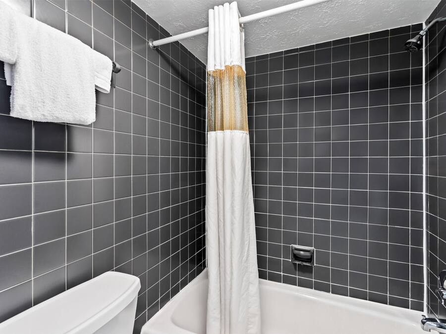 A modern bathroom with a white bathtub, a shower curtain, and a toilet.