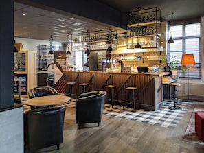 Een bar met krukken, een toonbank en flessenrekken.