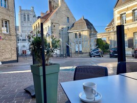 Una mesa de café con una taza y platillo, una planta en maceta y vistas de edificios históricos.