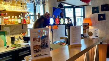 Un espace bar avec un présentoir à menus, des tabourets de bar et une variété de bouteilles exposées sur des étagères.