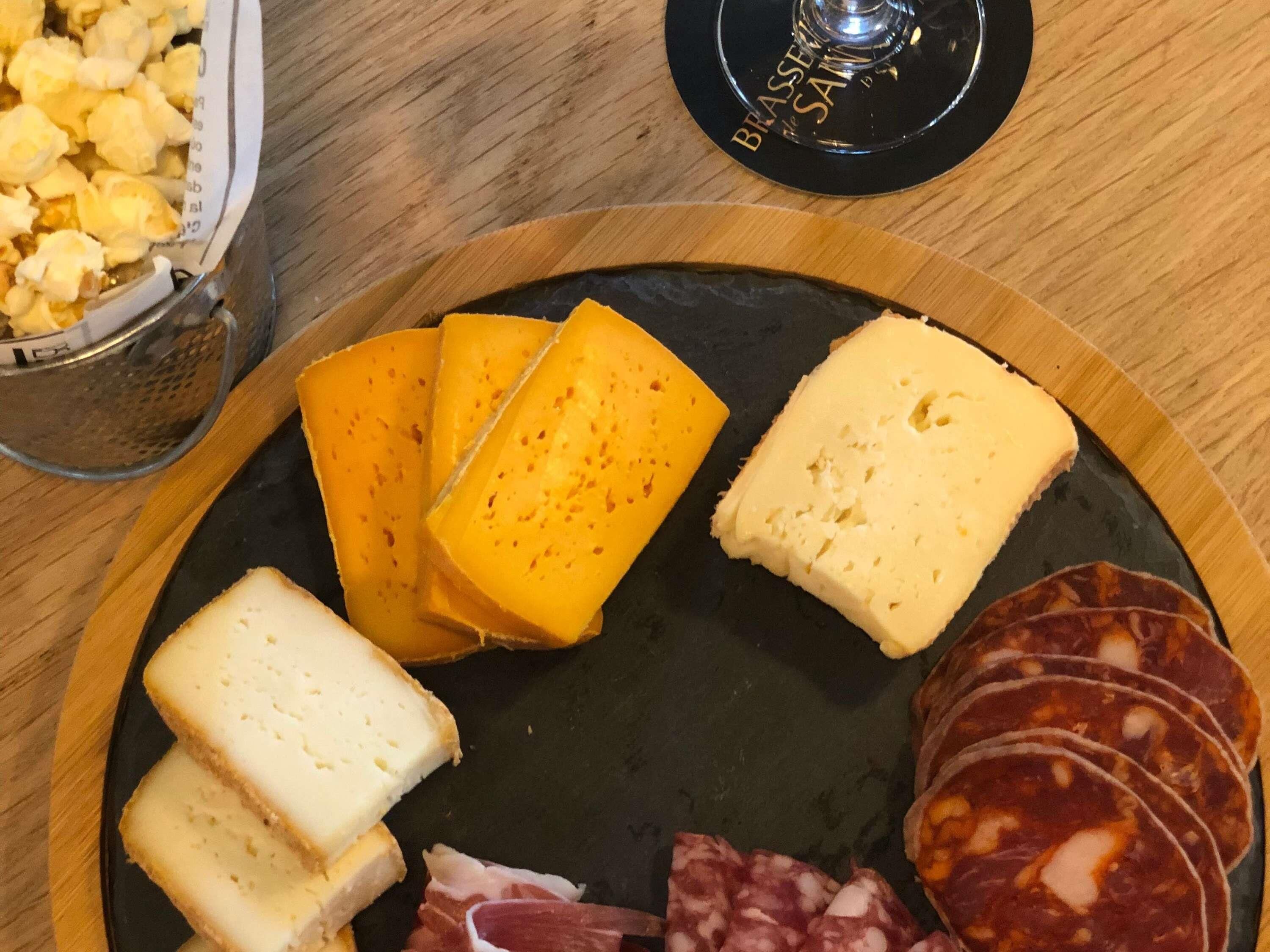 Una tabla de quesos y embutidos sobre un plato de pizarra negra.