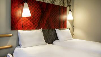 Une chambre d’hôtel avec deux lits, un mur décoré d’un motif imitant le marbre et des luminaires suspendus.