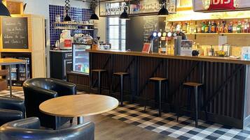 Een bar met krukken, een toonbank en een koelkast.