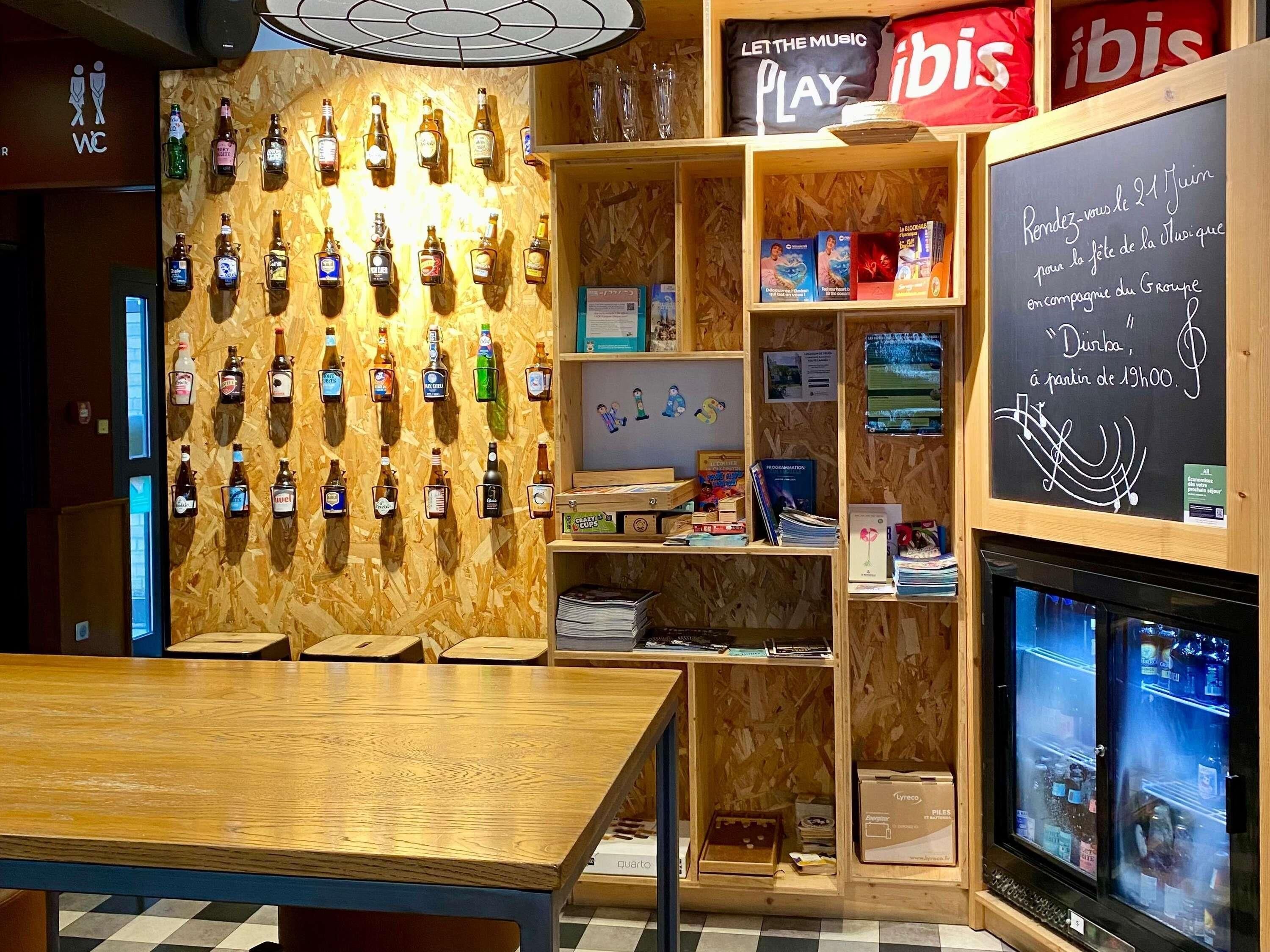 A bar area with wooden shelves, a wall-mounted liquor display, and a chalkboard with text.