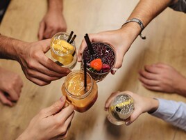 Un grupo de personas sosteniendo bebidas formando un círculo.