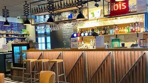 Un espace bar avec des tabourets, un comptoir où sont exposées les boissons et un panneau affichant le menu.