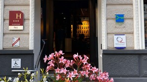 L’entrée d’un hôtel, avec un panneau indiquant une entrée accessible aux personnes handicapées, un panneau indiquant l’emplacement des plaques d’immatriculation et un panneau représentant un symbole de clé.