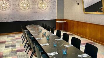 A conference room with a long table, chairs, and a brick wall.