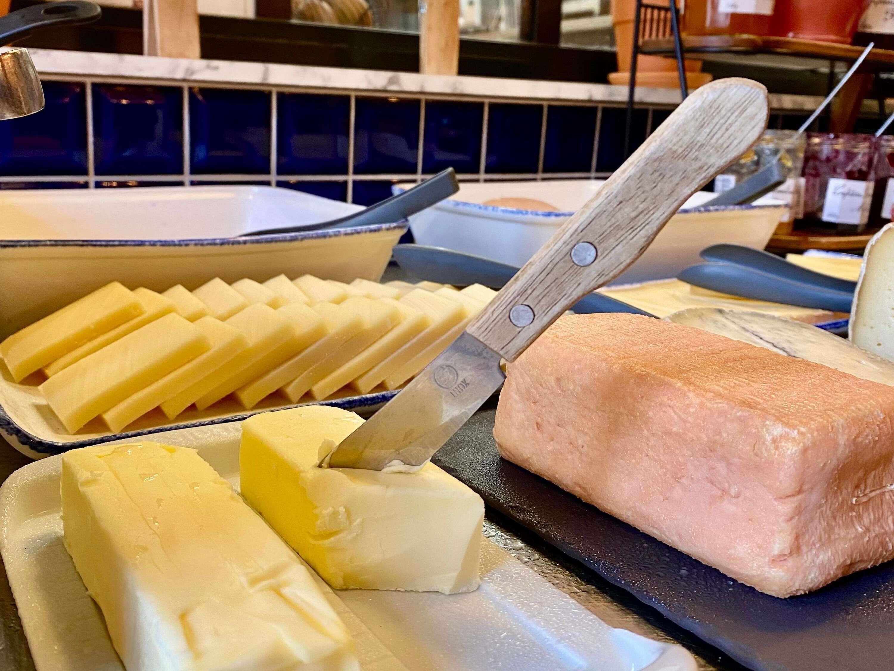 Une planche à découper avec un couteau, un morceau de beurre et un plateau de tranches de beurre.