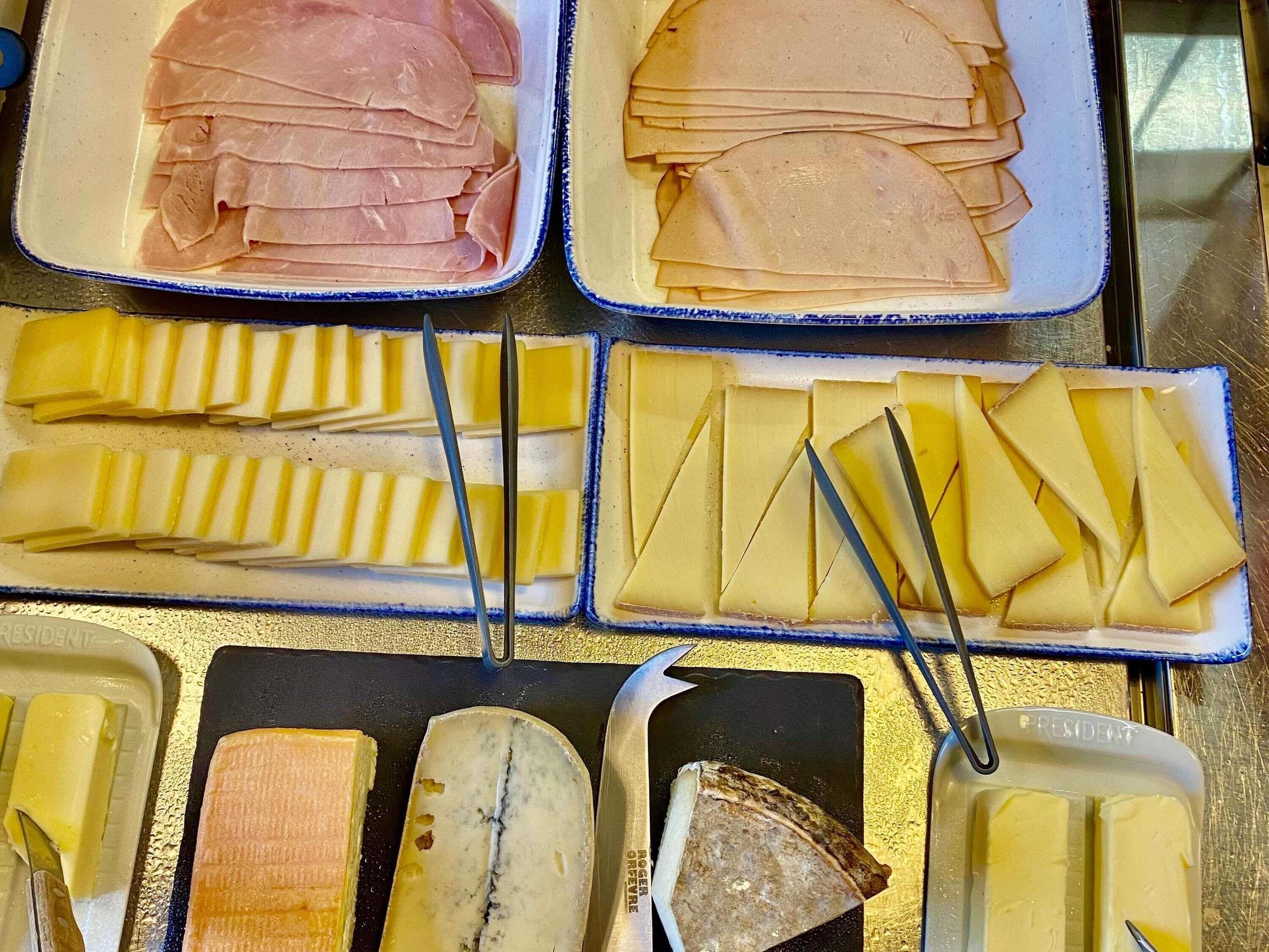 Verschiedene Käsesorten und Fleischwaren sind auf Platten angerichtet.