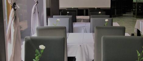 A restaurant with a view of the Eiffel Tower, white tablecloths, and grey chairs.
