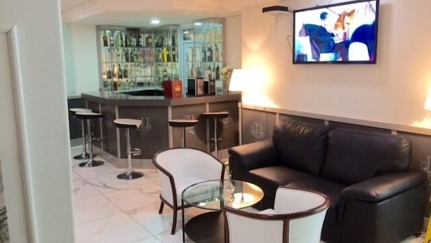 A modern living room with a leather sofa, a glass coffee table, and a TV mounted on the wall.