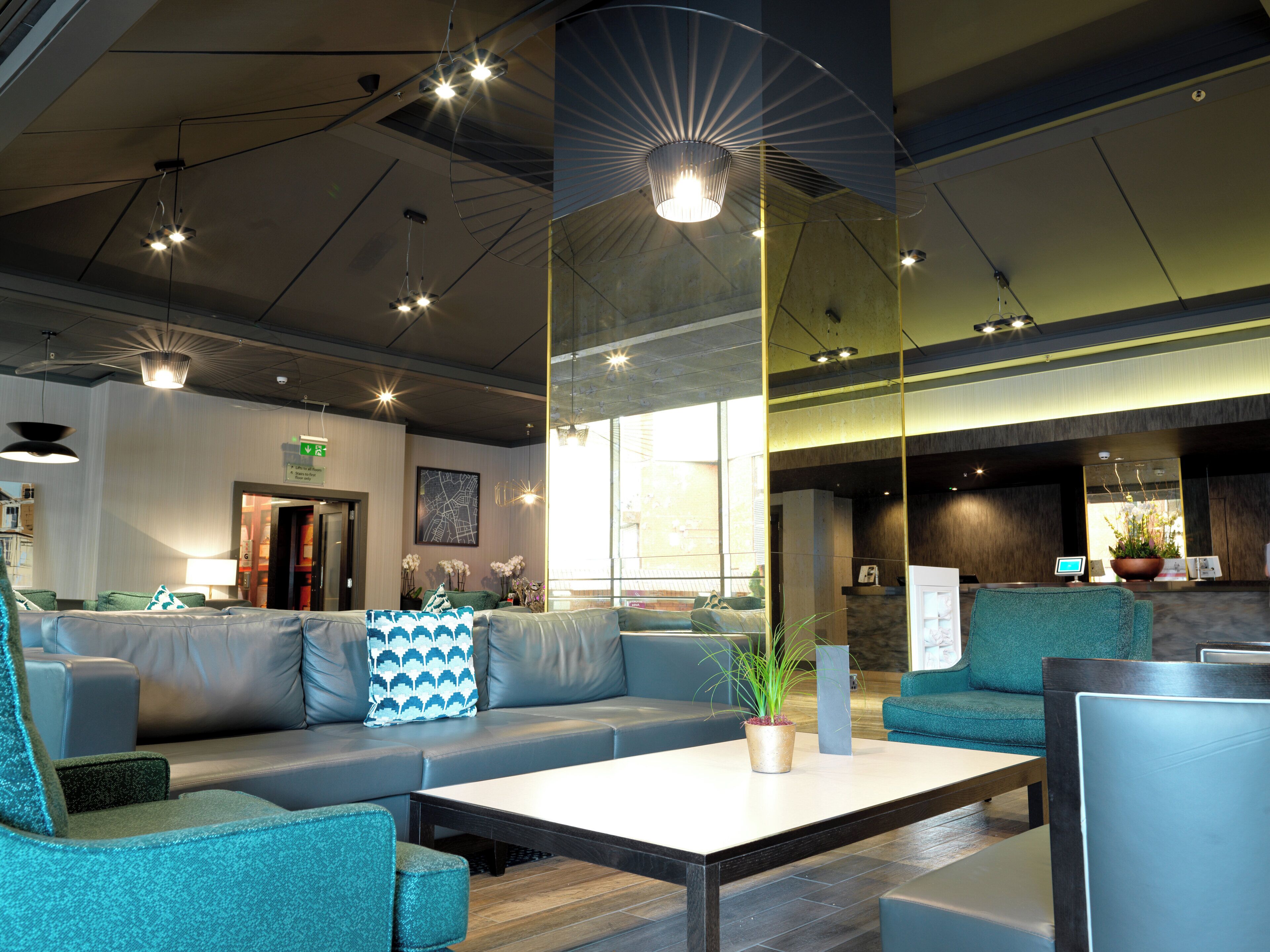 A modern lobby with seating areas, a reception desk, and a large window providing natural light.