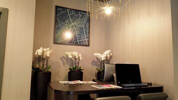 A modern office space with a desk, two chairs, a laptop, a desktop computer, and three orchid plants.