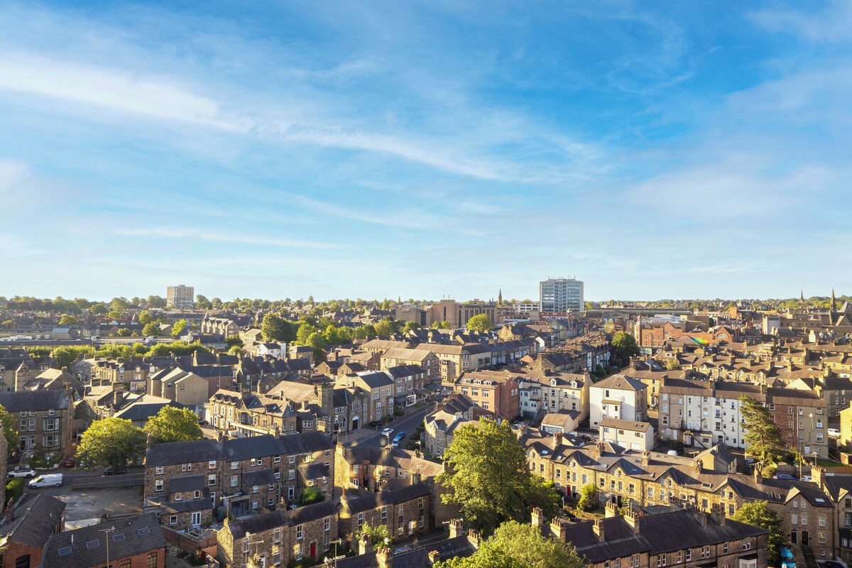 A densely packed urban area with a mix of residential and commercial buildings, including a prominent high-rise in the distance.