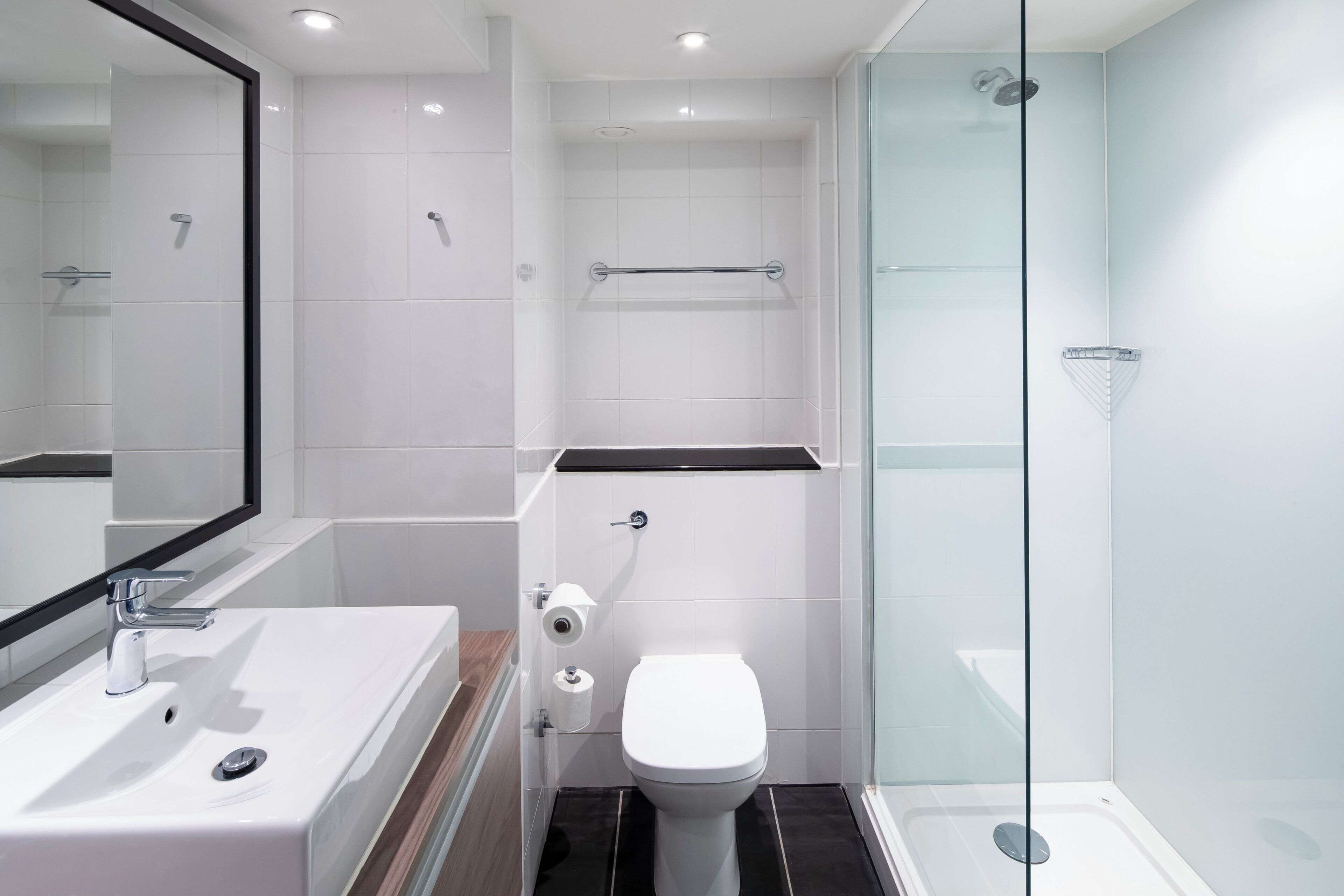 Un bagno moderno con cabina doccia in vetro, un lavandino bianco e il water.