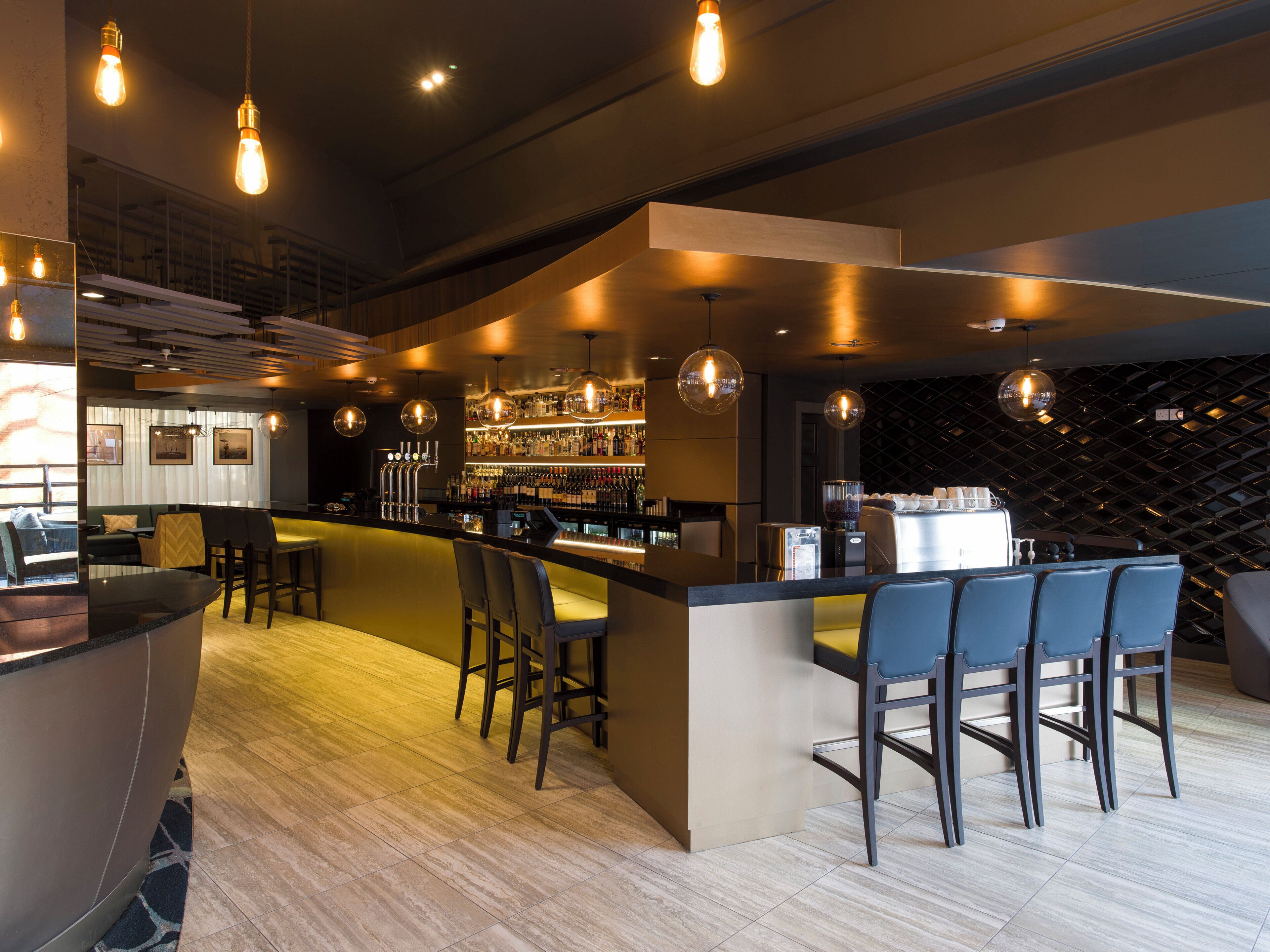 Zona de bar con asientos, barra y estante para vinos.