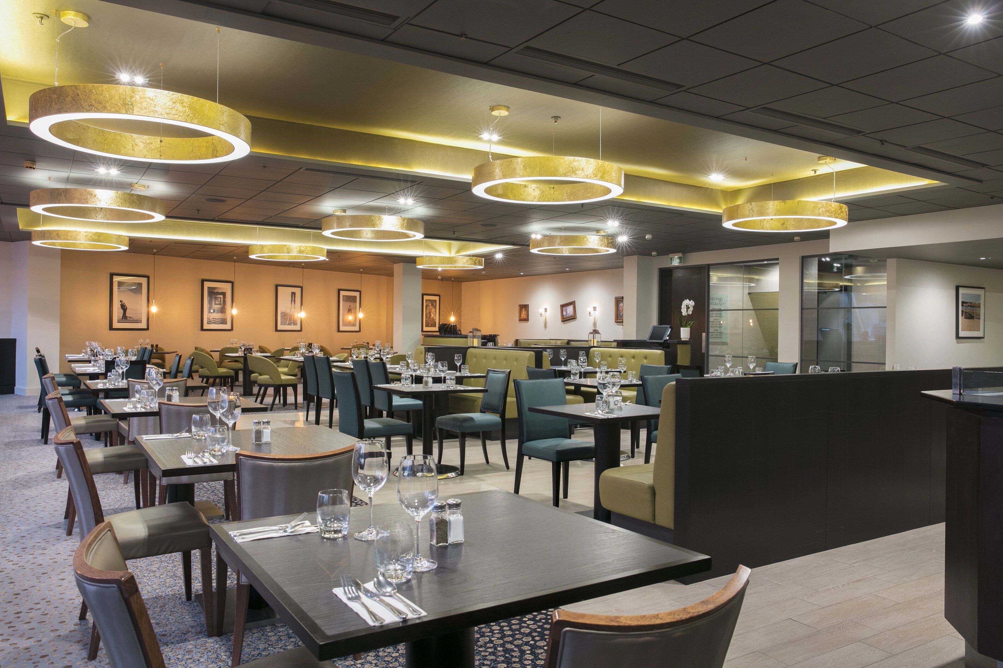 Un restaurante con varias mesas, sillas y una zona de bar.