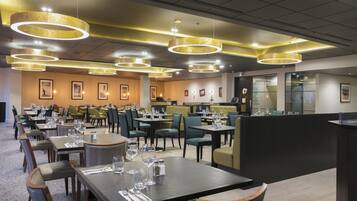 Un restaurante con varias mesas, sillas y una zona de bar.