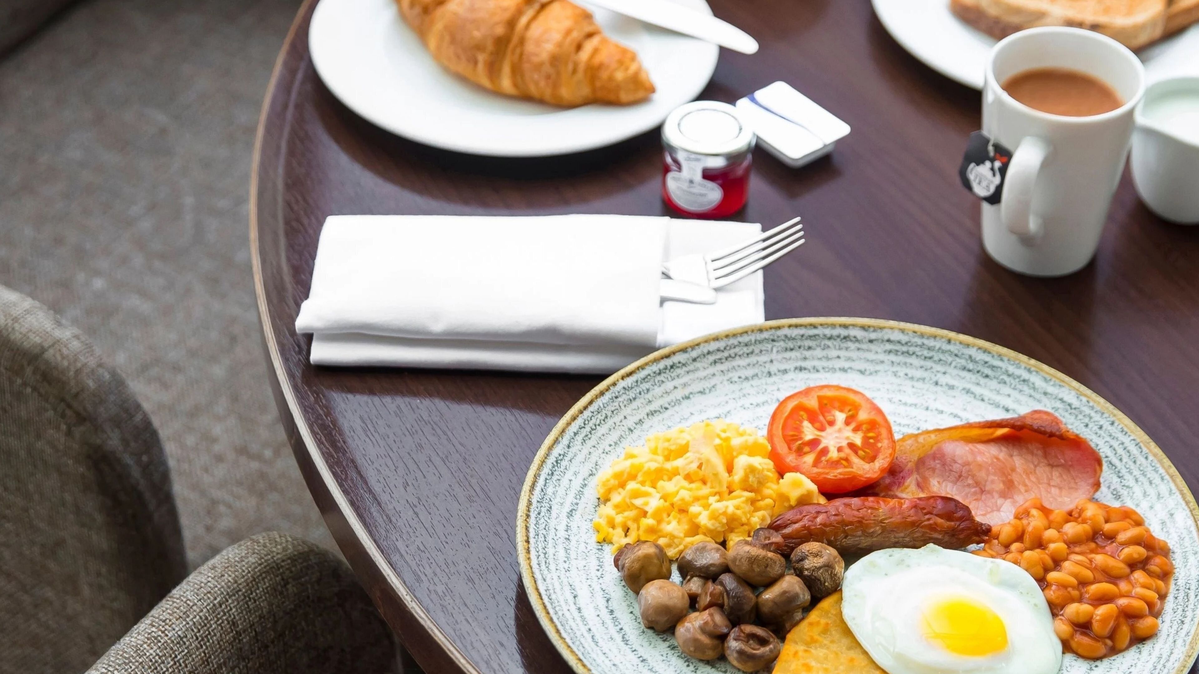 Bandeja de desayuno con huevos, salchichas, frijoles, tomates y tostadas.