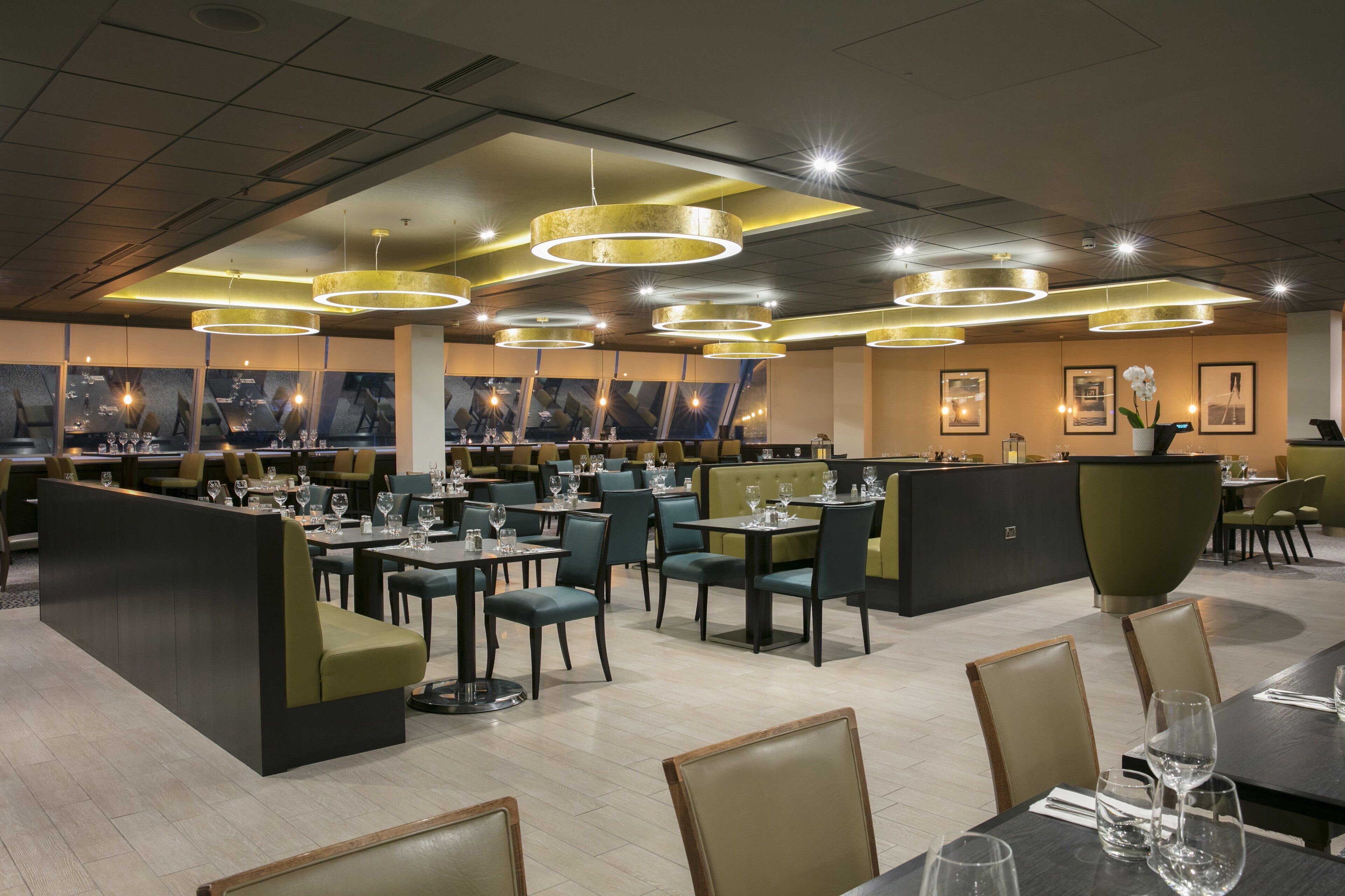 A restaurant with multiple dining areas, including booths and tables, and modern pendant lighting.