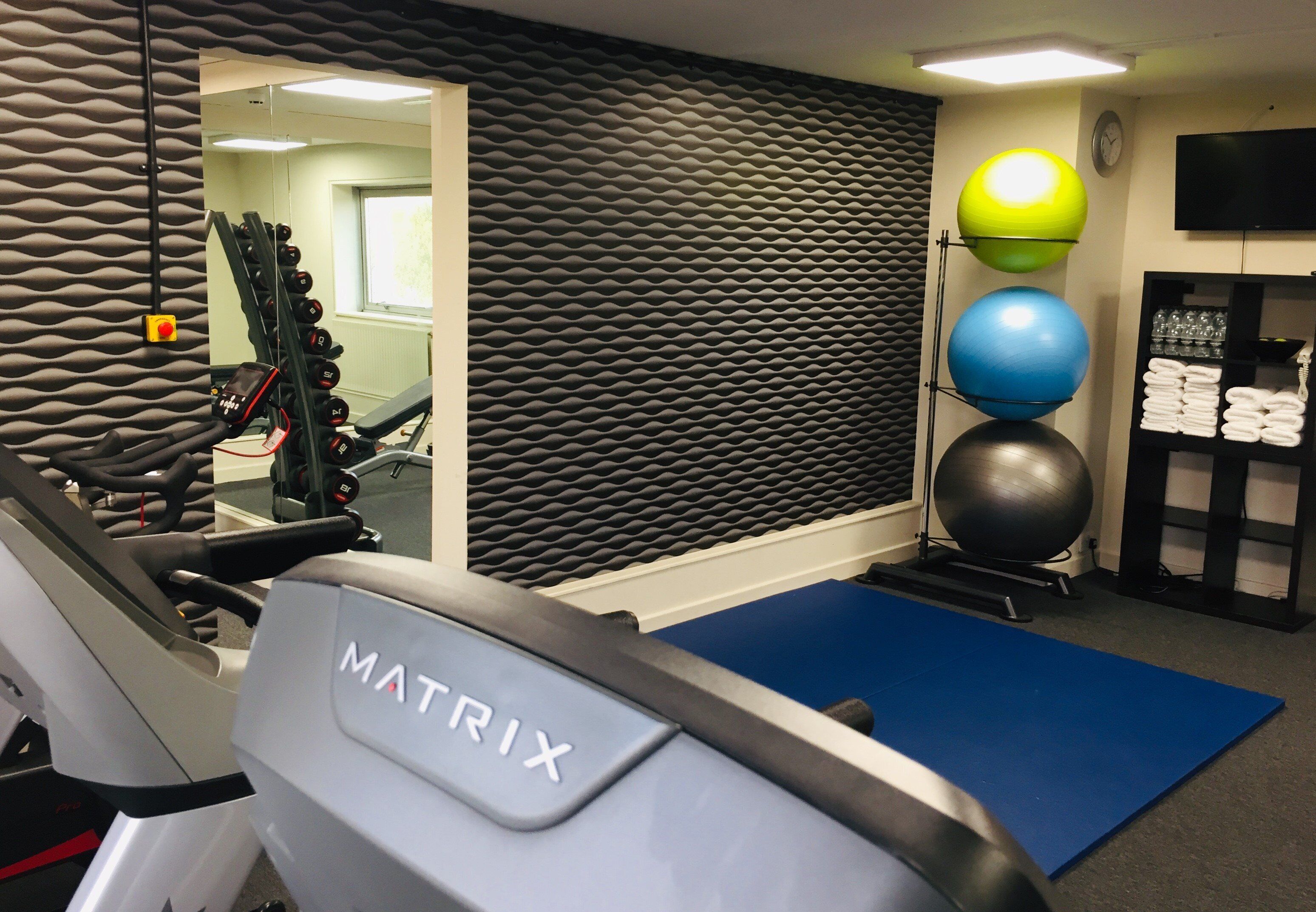 A gym with a treadmill, exercise balls, and a mirrored wall.