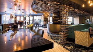 Eine moderne Bar mit einer gebogenen Theke, Sitzmöglichkeiten und einer Wendeltreppe.