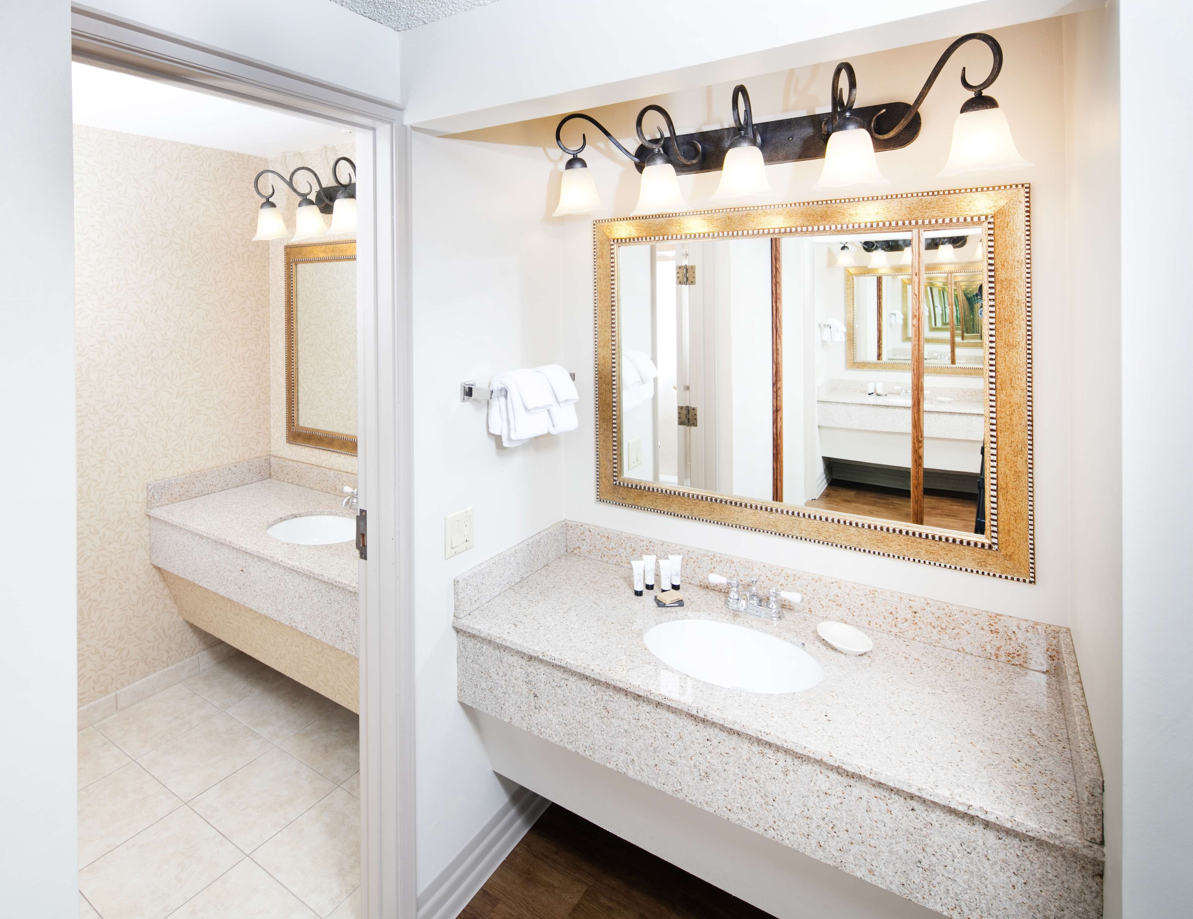 A bathroom with two sinks, a large mirror, and a vanity with toiletries.
