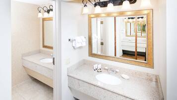 A bathroom with two sinks, a large mirror, and a vanity with toiletries.