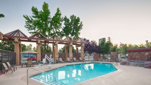 A swimming pool with lounge chairs and a covered seating area.