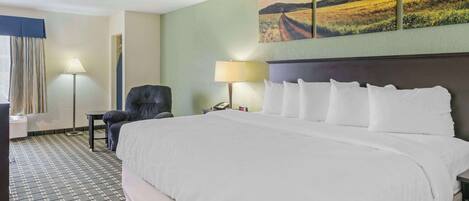 A hotel room with a large bed, two bedside lamps, a chair, a desk, and a painting on the wall.
