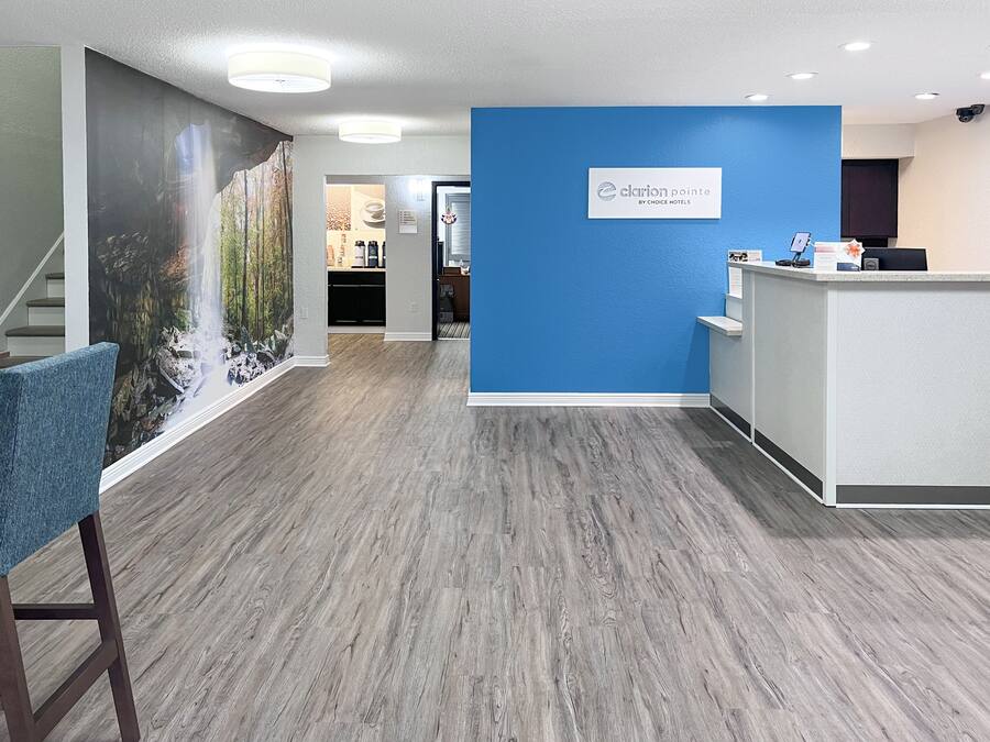 A hotel reception area with a blue accent wall, a reception desk, and a staircase leading to another floor.