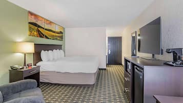 Una habitación de hotel con cama, escritorio, televisor y un cuadro en la pared.