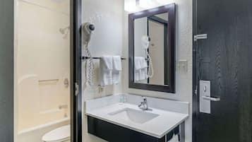 Un bagno con lavandino bianco, uno specchio, un asciugacapelli e una doccia.