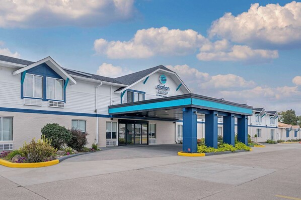 A Clarion Pointe hotel with a covered entrance, a parking lot, and a landscaped area with shrubs and flowers. - Clarion Pointe Jasper (Jasper)