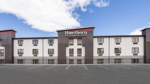 A Hawthorn Extended Stay hotel with a modern facade, multiple windows, and a parking lot.