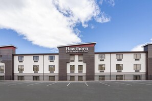 A Hawthorn Extended Stay hotel with a modern facade, multiple windows, and a parking lot.