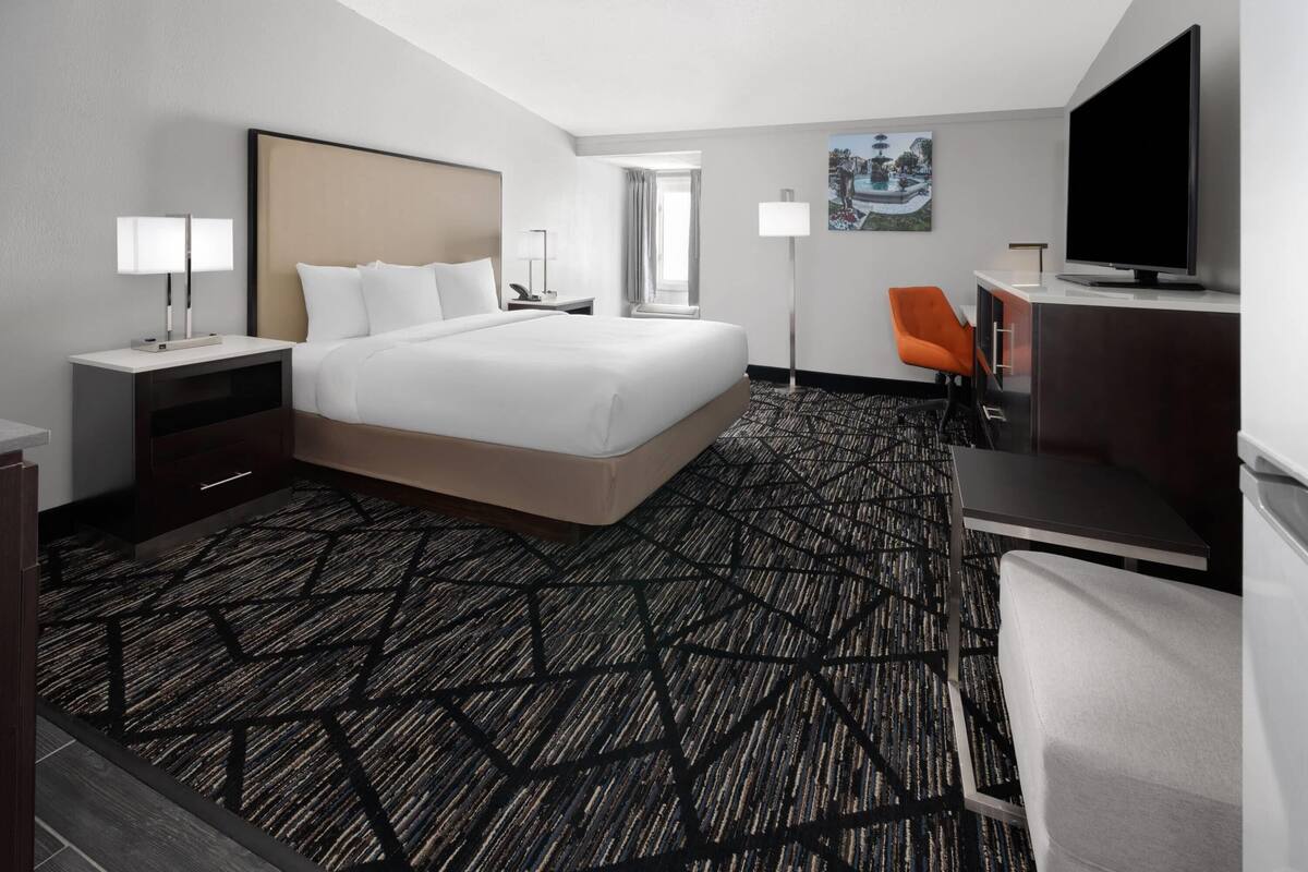 Ein Hotelzimmer mit einem großen Bett, einem Schreibtisch, einem Fernseher und einem Sessel.