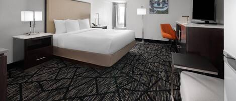 Une chambre d’hôtel avec un grand lit, un bureau, une télévision et une chaise.