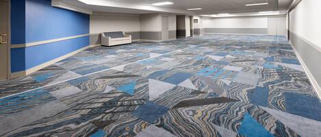 A spacious hotel lobby with a patterned carpet, a reception desk, and a blue accent wall.