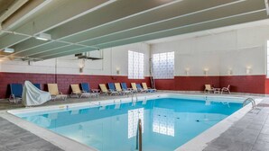 An indoor swimming pool with tiled walls, a clear pool, and sunlit windows.