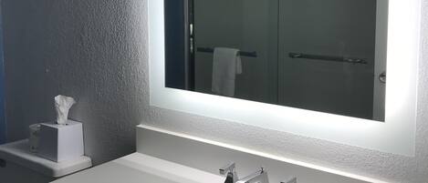 Um banheiro moderno com um espelho grande, duas pias e um porta-toalhas.